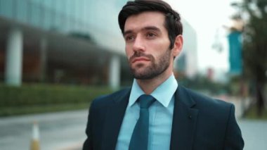 Şehir manzarasında kameranın yanında yürüyen iş adamının yakın çekimi. Proje yöneticisi bulanık arkaplanlı olarak iş yerine gidiyor. Yakışıklı yatırımcı resmi takım elbise giyer, görüşmeye hazırlanır, iş görüşmesi yapar. Sevinçli..