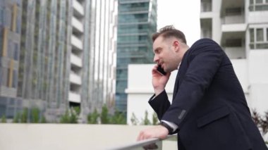 Zeki beyaz iş adamı, çatıda dururken iş arkadaşını mali strateji planlaması için arıyor. Proje yöneticisi pazarlama ekibiyle iletişim kurmak için cep telefonunu kullanıyor. Yaşam tarzı. Urbane.