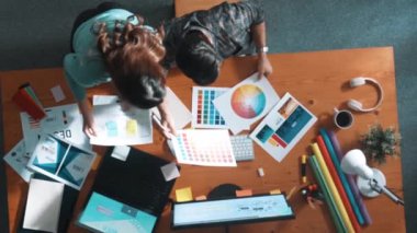 Tasarımcı yazma fikri ekrana bakarken proje yöneticisinin üst görünümü. Akıllı iş adamlarını kapat ve tasarımcı palete bakarken logo tasarımı fikrini açıkla. Sempozyum.