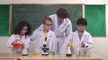 Kafkasyalı zeki öğretmen, meraklı öğrencilerin laboratuardaki deney kabına renkli sıvı dökmesini destekler. Yaratıcı çocuklar deney yapmaya ve biyokimyasal örnekleri incelemeye konsantre olurlar. Pedagoji.