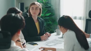 İş kadını ev modeli hakkında tartışırken işadamı mimari modelle ilgili belgeleri toplantı masasında oturmuş etrafa dağılmış planlarla etrafa dağıtıyor. Hizalama.