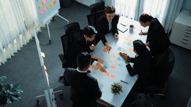 Akıllı yönetici finansal grafiğinin üst görüntüsünden çeşitli takımlara geçerken, bir grup çok kültürlü iş adamı toplantıda hisse yatırım grafiği kullanarak pazarlama stratejisi planlıyorlar. Müdürlük.