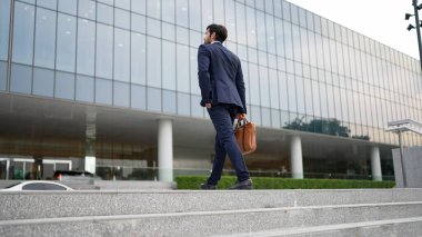 Ofise giderken merdivenlerden çıkan başarılı bir iş adamı bacağı. Proje yöneticisi iş yerini değiştiriyor, yeni bir şey keşfediyor, gelişiyor, terfi ediyor ya da gün ışığına çıkıyor. Ayağa kalkın. Sevinçli..