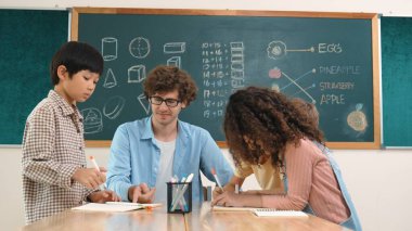 Zeki öğretmen, çeşitli çocuklar sınıf çalışması yapmak için birlikte çalışırken farklı çocukların zihin haritası çizdiği fikri açıklıyor. Çekici eğitmen öğretmek ve çalışmak hakkında konuşmak. Pedagoji.