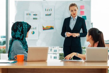 Çok kültürlü çalışma grubu. Farklı etnik kökenden iş kadınları, Kafkasyalı, Asyalı ve Araplardan oluşan bir ekip ofiste dizüstü bilgisayarla birlikte çalışıyor. Çok ırklı takım çalışması konsepti. uds