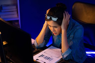 Stresli, genç, güzel Asyalı yaratıcı proje yaratıcısı sosyal medyayı araştırmak için bilgisayara bakıyor ve geceleri daha çok neon modern ofisin planlama kanalı stratejisine ulaşılıyor. Taktik.