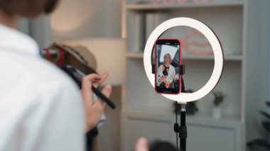 Arka plan etkileyicisi, vlog video gözden geçirme makyaj primi sosyal medya ya da blog kullanarak akıllı telefon yayınıyla canlı çekim yapıyor. İnternetteki pazarlama kaydı için kozmetik stüdyosu ışıklandırması olan kız.