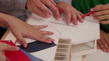 Mimari ekipman kullanarak yavaş çekim ev tasarımcısı bir plan çizerken, iç mimari tasarımcı da müşterilerin talebine göre renk örneklerinden uygun renkler seçiyor. Değiştirilmiş