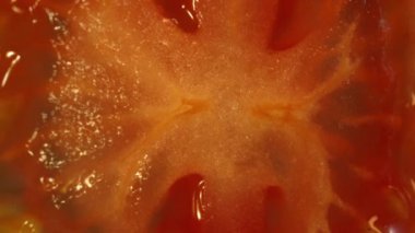 Dilimlenmiş domatesin makro fotoğrafı. Domates eti sulu ve yumuşak görünüyor, hafif bir sertlikle. Dilimlenmiş domates ışığın altında parlıyor, tazeliklerini ve olgunluklarını gösteriyor. Geliştirilebilir.