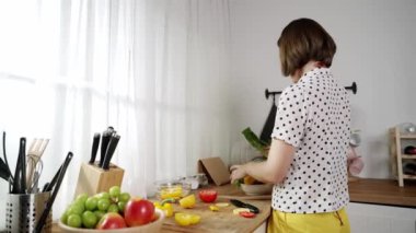 Kafkaseli anne kahvaltıda sebze pişirirken mutlu anne de modern mutfakta salata için taze malzemeler hazırlıyor. Hizmetçi sağlıklı yemek pişiriyor. Dikkat konsepti. Pedagoji.