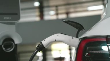 Şehir merkezindeki kapalı otoparkta yavaş çekimde EV elektrikli araba şarj oluyor. Şehir merkezinde sürdürülebilirlik yeşili, yeniden şarj edilebilir elektrikli araç iç organları.