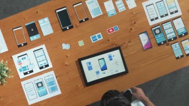 Ux Ui tasarımı kullanarak strateji planlarken plan geliştirmeye çalışan yetenekli Kafkas yazılım geliştiricisinin üst görünümü. Akıllı programcı ayakta duruyor ve tablet tasarım programı üzerinde çalışıyor. Cemaat.