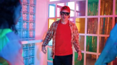 Kafkas dansçısı dans ederken çeşitli arkadaşları gece kulübünde neon ışıkta ayak seslerine bakıyor. Çoklu etnik kökenli hipsterin serbest stil müziğe geçişi ve mutlu bir adamın kameraya bakışıyla. Mutluluk.