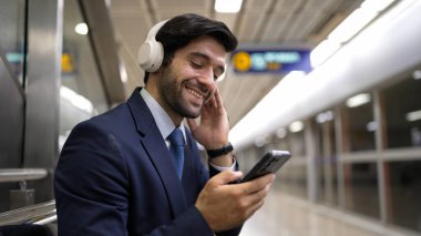 Tren istasyonunda geçmişi bulanık bir şekilde beklerken kulaklıkla müzik dinleyen zeki bir iş adamı. Yetenekli proje yöneticisi cep telefonu tutarken dinlenme sesi dinlemeyi sever. Sevinçli..