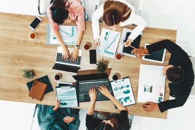 Modern ofisteki iş adamları ve iş kadınlarıyla grup toplantısındaki iş adamlarının en üst düzey görüşü, masada dizüstü bilgisayar, kahve ve belge ile. Kurumsal şirketler uds