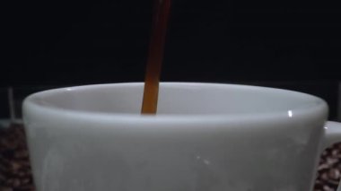 Kahve makinesi fincana siyah arka planda aromatik sıcak kahve dolduruyor. Sıcak kahve ya da espresso beyaz kahve bardağına dökülüyor ve kaynamış suya dökülüyor. Geliştirilebilir.