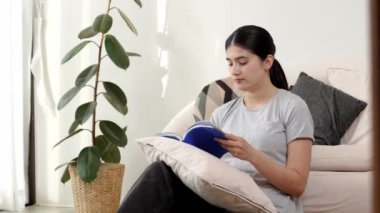 Kanepede oturan bir kadın ders kitabı okuyarak sosyal ve mesleki teknoloji bilgisini artırır ya da akıllı bir anne olmak için çocuk yetiştirir. Hayat boyu öğrenme konsepti. Uyumsuzluk.