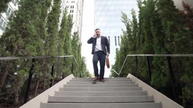 Mutlu iş adamı merdivenlerden inip akıllı telefon kullanarak müdürü arıyor. Yöneticinin pazarlama ekibinden bahsetmesi ve merdivenlerden inerken telefonla finansal strateji planlaması. Urbane.