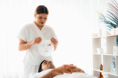 Kaplıca salonunun sakin, modern gündüz atmosferi. Kadın müşteri yüz maskesi takarak kendini yenilemeye çalışıyor. Yüz bakımı ve güzellik kozmetolojisi prosedürü. Sessiz.