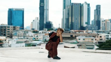 Profesyonel Asyalı break dansçı B çocuk dansı yaparken çatıda çok kültürlü arkadaşlar var. Genç modern dans grubu hip hop hareketi yapıyor. Tarz, moda, aksiyon. Açık hava sporu 2024. Hiphop.