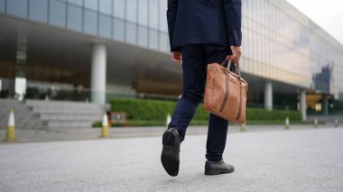 Çantayı tutarken yürüyen yetenekli iş adamının yakın çekimi. Proje yöneticisinin bacağa odaklanmış görüntüsü. Seyahat, taşınma, seyahat, yeni bir iş bulma, iş değiştirme. Arkadan bak. Sevinçli..
