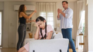 Sinirli ve mutsuz genç bir kız oturma odasında ebeveyninin tartışması yüzünden gerginliğin ortasında kanepede oturuyor. Sağlıksız ev hayatı ve travmatik çocukluk depresyon senkronlarına dönüşür.