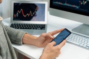 Akıllı borsa yatırımcıları ekranda akıllı telefon ile piyasa borsasını işaret ederek dizüstü bilgisayarın yanı sıra en yüksek dinamik yatırım oranını göstererek, modern işyerindeki veri planlamasına odaklanıyorlar. Bireysel.