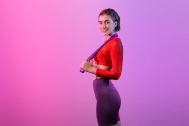 Vücut uzunluğunun tamamı atletik ve sportif, elastik direnç bandıyla izole edilmiş arka planda duran genç bayanı çekiyordu. Sağlıklı aktif ve vücut bakımı yaşam tarzı.