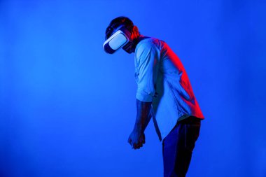 VR gözlüklü beyaz adam golfte hareket ediyor ve neon arka planda duruyor. Profesyonel oyuncu sanal dünyaya fütüristik teknoloji yeniliğiyle giriyor. Sapma.