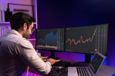 Akıllı tüccar işadamı, karanlık oda gecesinde neon ışıklı ofisteki arama pazarında yüksek kârla ekranda bilgisayar ve bilgisayar üzerinde dinamik borsa yatırımları üzerinde yoğunlaşıyor. Tahmin et..