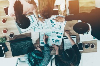 Modern ofisteki iş adamları ve iş kadınlarıyla grup toplantısındaki iş adamlarının en üst düzey görüşü, masada dizüstü bilgisayar, kahve ve belge ile. Kurumsal şirketler uds