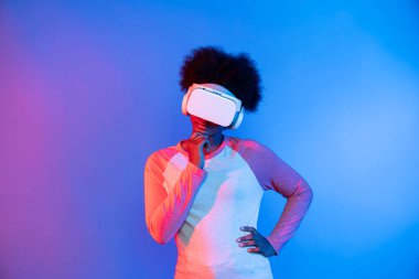 Profil, VR gözlük takan genç ve güzel Afrikalıların mavi ve pembe neon ışıklı arkaplanda izole olduğunu düşünüyor. Teknoloji ve dijital yenilik 3 boyutlu hologram gramında. Entrika.