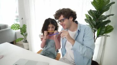 Komik beyaz bir baba ve Amerikalı bir çocuk dudak ve burun arasına kalem koyarken komik bir yüz ifadesi takınıyorlar. Birlikte mühendislik komut yazma ve masadaki dizüstü bilgisayarda yapay zeka üretme üzerine sevimli bir aile çalışması. Pedagoji.