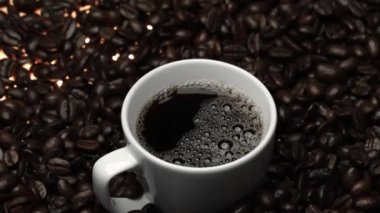 Kahve ya da kahve çekirdekli espresso manzarası. Taze kavrulmuş kahve çekirdeğini yakın çekimde ahşap masanın etrafına bir fincan americano ve aromatik akarsu ve tohum dumanı serpin. Geliştirilebilir.