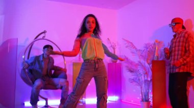 İspanyol hipster renkli kıyafetler giyer ve serbest stil müziğe el sallar. Profesyonel break dansçı neon ışıklarıyla ve modern stüdyo arkadaşlarıyla coşkuyla dans ediyor. Mutluluk.