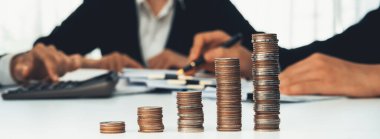Büyüyen madeni para yığını iş yatırımını ve ekonomik büyümeyi simgeliyor. Finansal hedefe ulaşmak ve maksimum kâr sağlamak için finansal planlama yapan iş adamları. Kurnaz.
