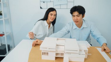 Becerikli mimari mühendisi ekip ölçümü ve ev modeline birlikte çalışırken karar verme ve toplantı odasındaki bina yapısı ve planlarla ilgili tartışmalar. Tertemiz..