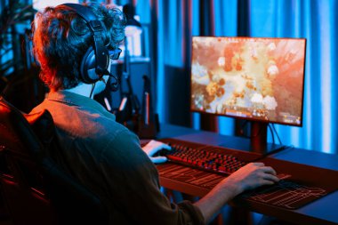 Savaş arenasında çoklu oyunlar takımıyla Moba 'da savaşan genç oyun flamasının sunucu kanalı, neon dijital ışık modern odasındaki arka görüntü ile bilgisayar monitöründe kulaklık takıyor. Toplayıcı.