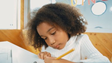 Smart african girl inspect data analysis while writing down on paper taking a note to solve a problem. Young clever student planning working project in STEM technology online classroom. Erudition.