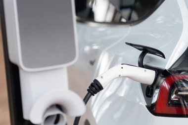 Kapalı EV şarj kolu fişe takıldı veya elektrikli arabaya bağlandı, EV araba aküsünü temiz çevre için sıfır CO2 emisyonu ile alternatif ve sürdürülebilir enerjiyle şarj etti. Kalıcı