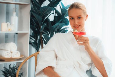 Güzellik ya da vücut bakımı güzellik salonu yaşam tarzı konsepti. Bornoz giyen bir kadın lüks otel kaplıcalarında ya da tatil odasında içkiyle rahatlıyor. Tatil ve boş zaman rahatlığı. Sessiz.