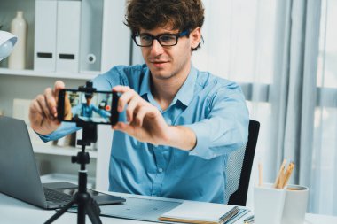 Etkilendiricinin sunucu kanalı akıllı telefon görüntüsünü bulanıklaştırıyor, ekipman kaydı hazırlamak için çevrimiçi yayın yapıyor, modern merkez ofisteki sosyal medyada portre arka planına odaklanıyor. Toplayıcı.