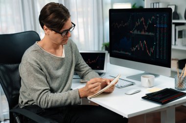 Gündelik işlerde çalışan zeki bir tüccar, dinamik yükseltilmiş borsa grafiğinin kar değerini analiz ederek, modern ofisteki kârlı yatırım listesi için kağıt üzerinde not alıyor. Bireysel.