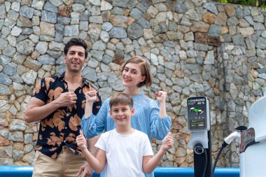 Elektrikli araçla aile seyahati, güzel bir aile arabası yeşil ve temiz enerjili. Kaya gibi sağlam bir arka plan ve sürdürülebilir çevre için çevre dostu araba yolculuğu. Kalıcı