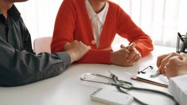 Çift, hastanede jinekoloğun aile planlaması bakımını tarif ederken, koca da genç eşini randevuyla teselli ediyor. Ağır çekim. Katı.