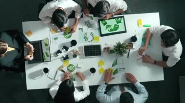 İş adamlarının rüzgar değirmeniyle toplantı masasında temiz enerji ve sürdürülebilir yatırım kullanımı, çevre grafiği ve ahşap ev modeli ile ilgili tartışmalarına tepeden aşağı bakış açısı. Hizalama.