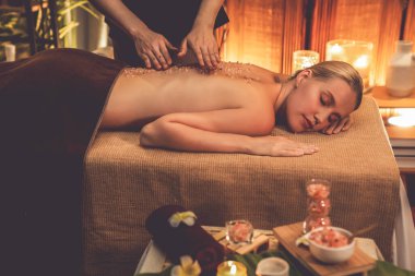 Lüks spa salonlarında sıcak mum ışığında cilt bakımı yaptıran kadın müşteri. Sağlık Spa vücut fırçasında tuz temizleme güzellik tedavisi. Sessiz.