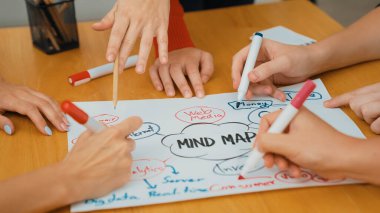 Yetenekli iş adamlarına yakın çekim yapmak beyin fırtınası yapmak, birlikte çalışmak, toplantı masasında zihin haritası ve renkli kalemler kullanarak pazarlama fikrini tartışmak. Eline odaklan. Tertemiz..