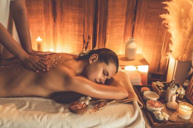 Lüks spa salonlarında sıcak mum ışığında cilt bakımı yaptıran kadın müşteri. Sağlık Spa vücut fırçasında tuz temizleme güzellik tedavisi. Sessiz.