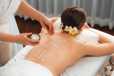 Lüks spa salonlarında sıcak mum ışığında cilt bakımı yaptıran kadın müşteri. Sağlık Spa vücut fırçasında tuz temizleme güzellik tedavisi. Sessiz.